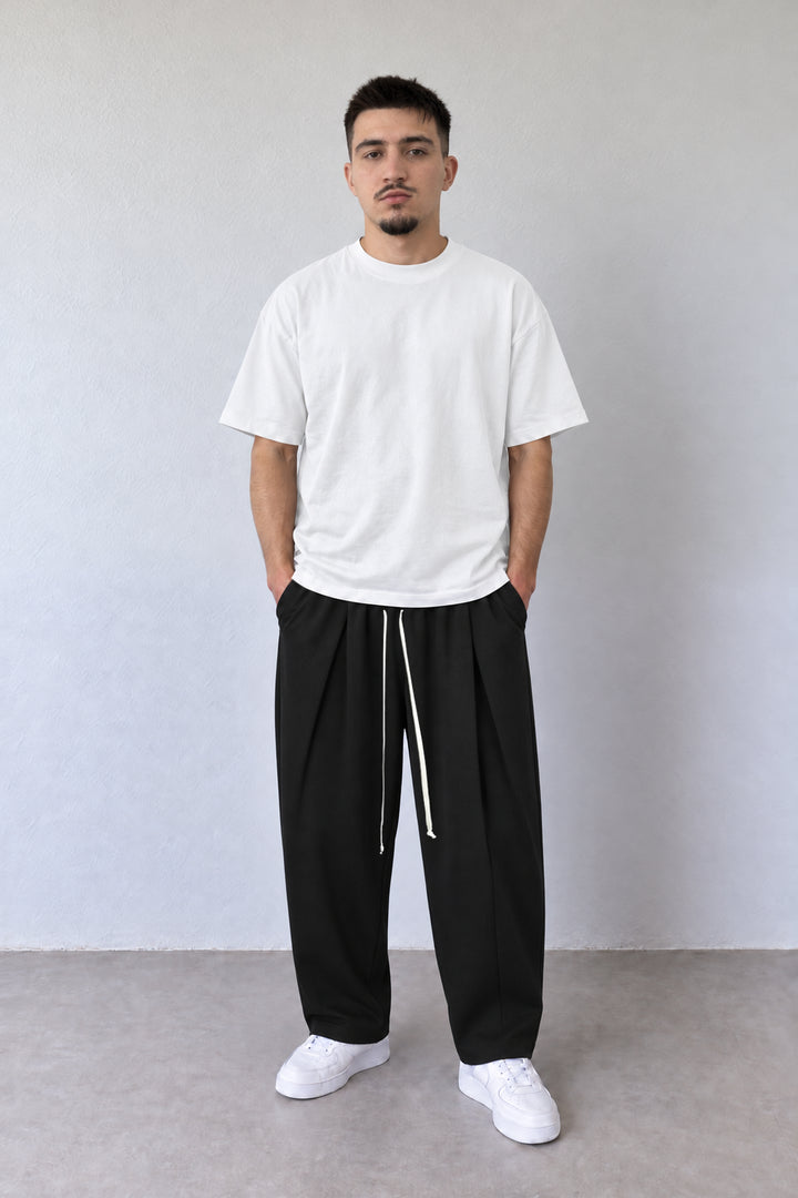 Pantaloni negri pentru bărbați DU-019106 cu pense și șnur lung, purtați cu tricou alb, vedere integrală.
