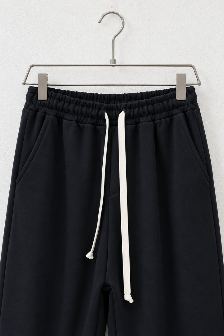 Detaliu al taliei elastice, buzunarelor și șnurului pantalonilor negri scuba
