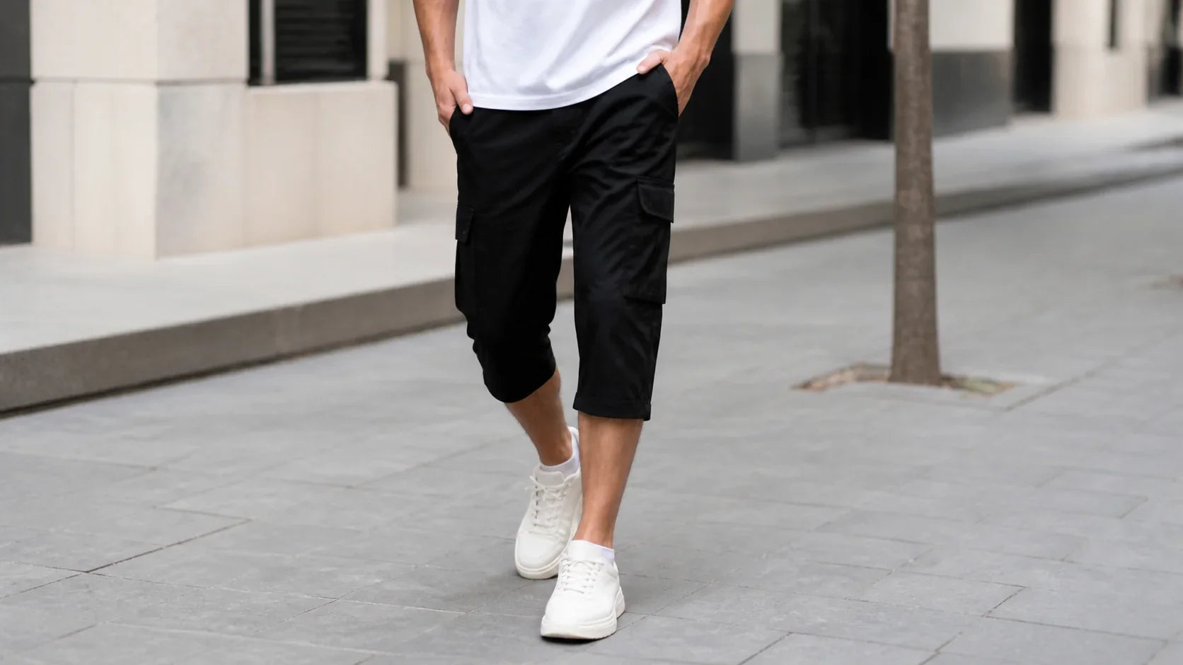 Bărbat purtând pantaloni trei sferturi cargo negri și sneakers albi