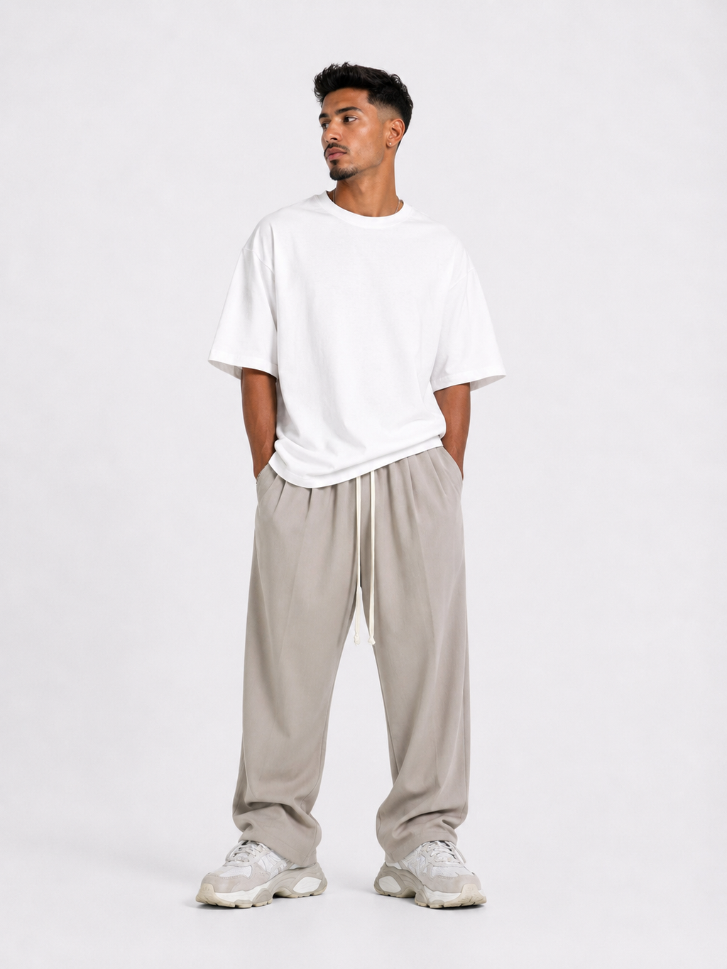 Bărbat purtând pantaloni bej oversized cu șiret lung într-un outfit streetwear modern și relaxat