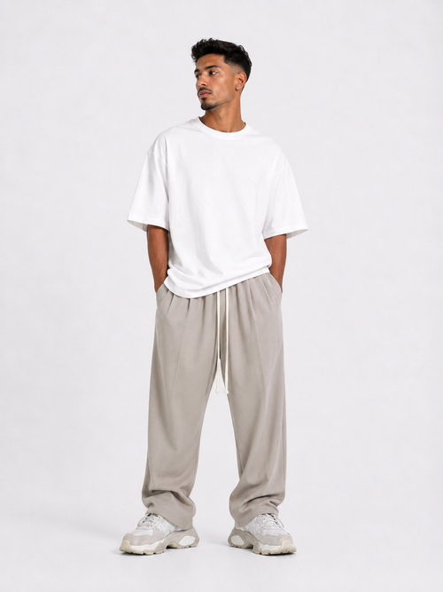 Bărbat purtând pantaloni bej oversized cu șiret lung într-un outfit streetwear modern și relaxat