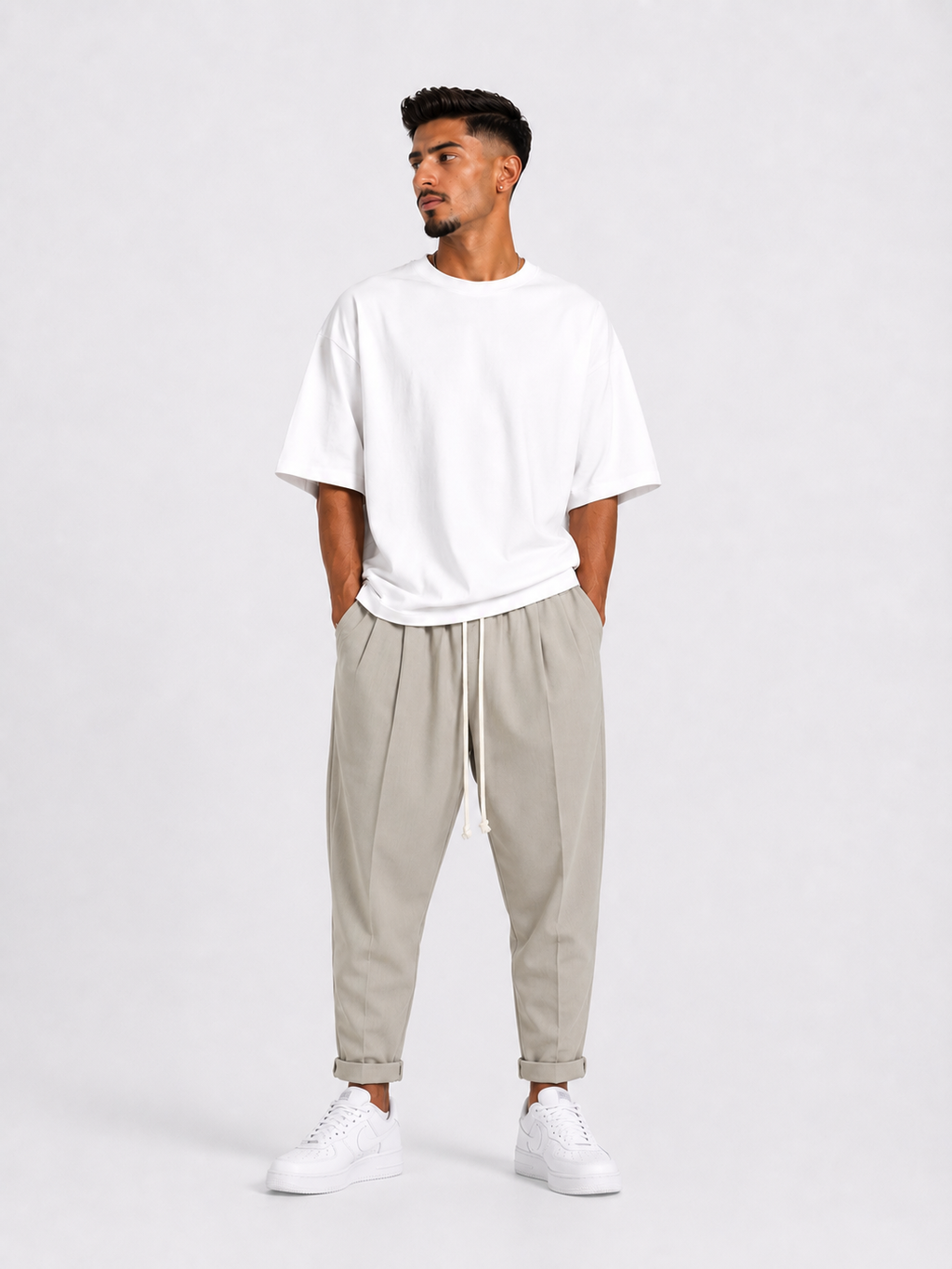 Bărbat purtând pantaloni crem slim cu șiret lung într-un outfit streetwear modern și relaxat.