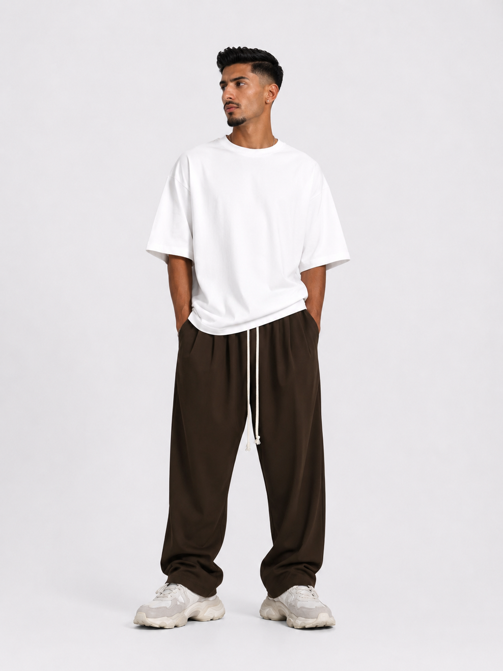 Bărbat purtând pantaloni maro oversized cu șiret lung într-un outfit streetwear modern și relaxat