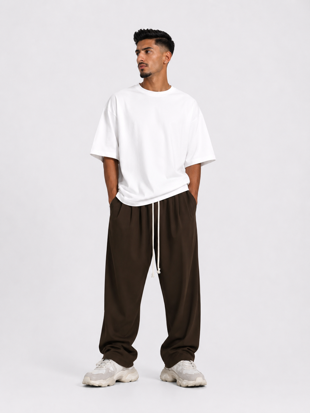 Bărbat purtând pantaloni maro oversized cu șiret lung într-un outfit streetwear modern și relaxat