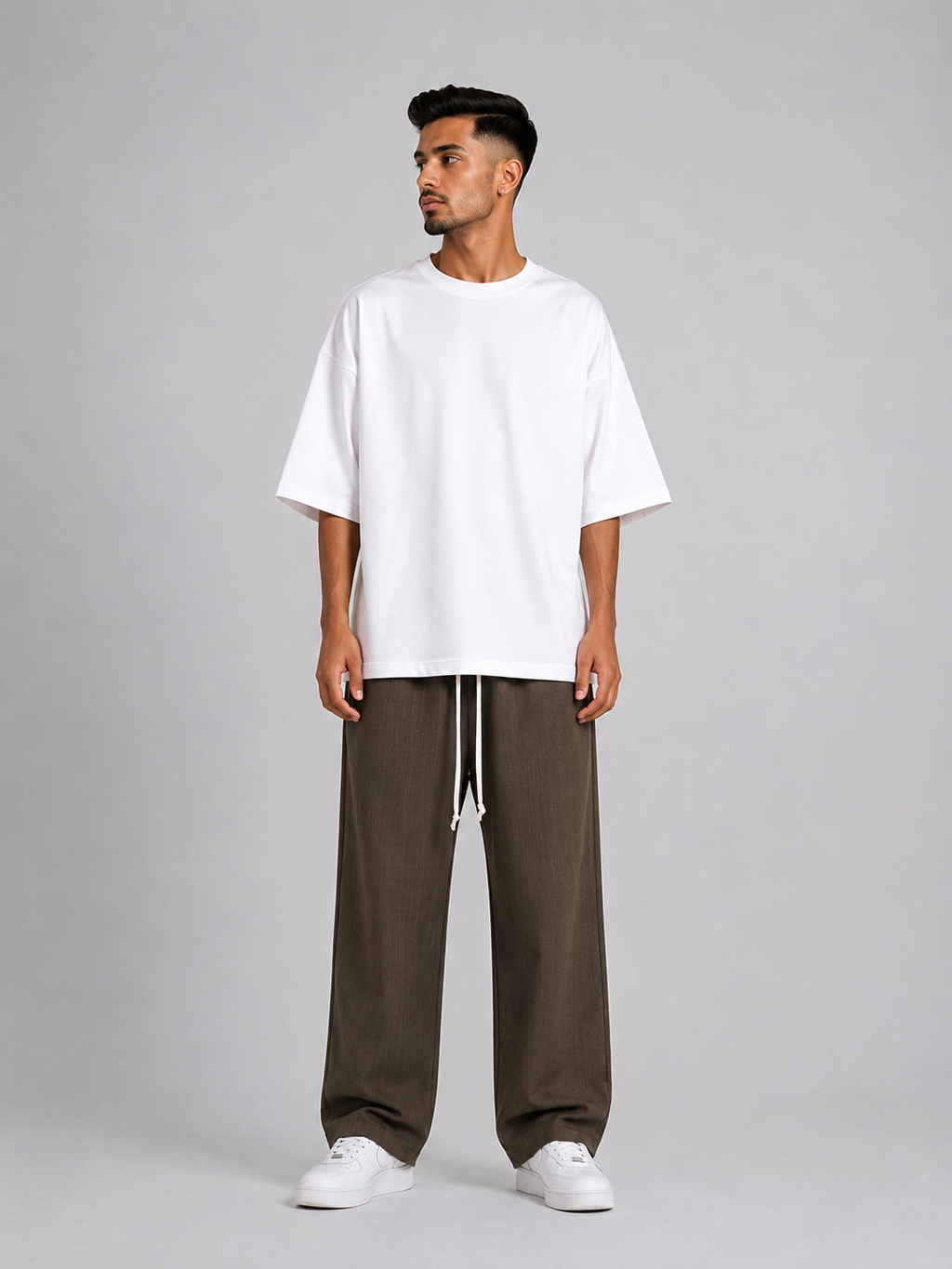 Bărbat purtând pantaloni maro wide leg cu șiret lung într-un outfit streetwear modern și relaxat.
