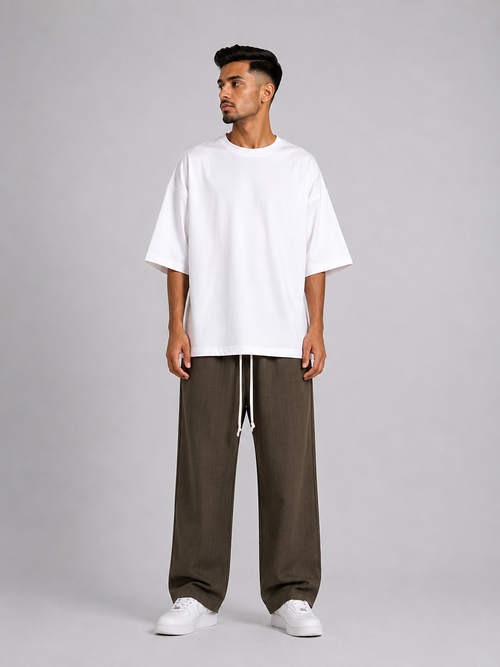 Bărbat purtând pantaloni maro wide leg cu șiret lung într-un outfit streetwear modern și relaxat.