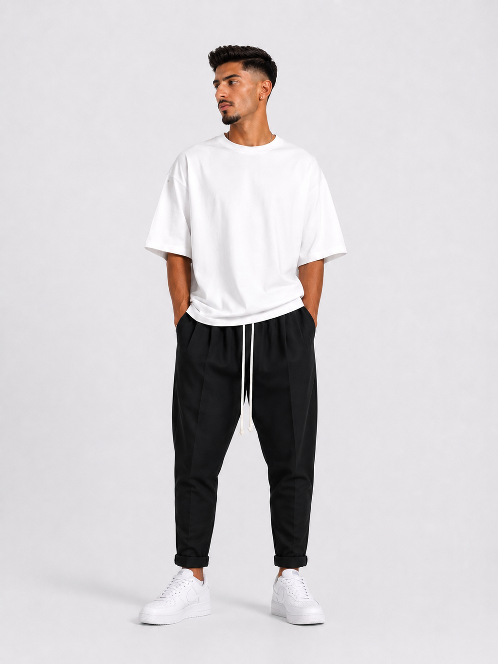 Bărbat purtând pantaloni negri slim cu șiret lung într-un outfit streetwear modern și relaxat.