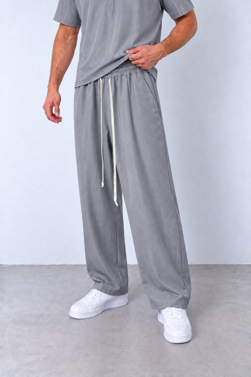 Pantalonii gri ai compleului FMT66/FMT67, detaliu din trei sferturi cu șnururi lungi