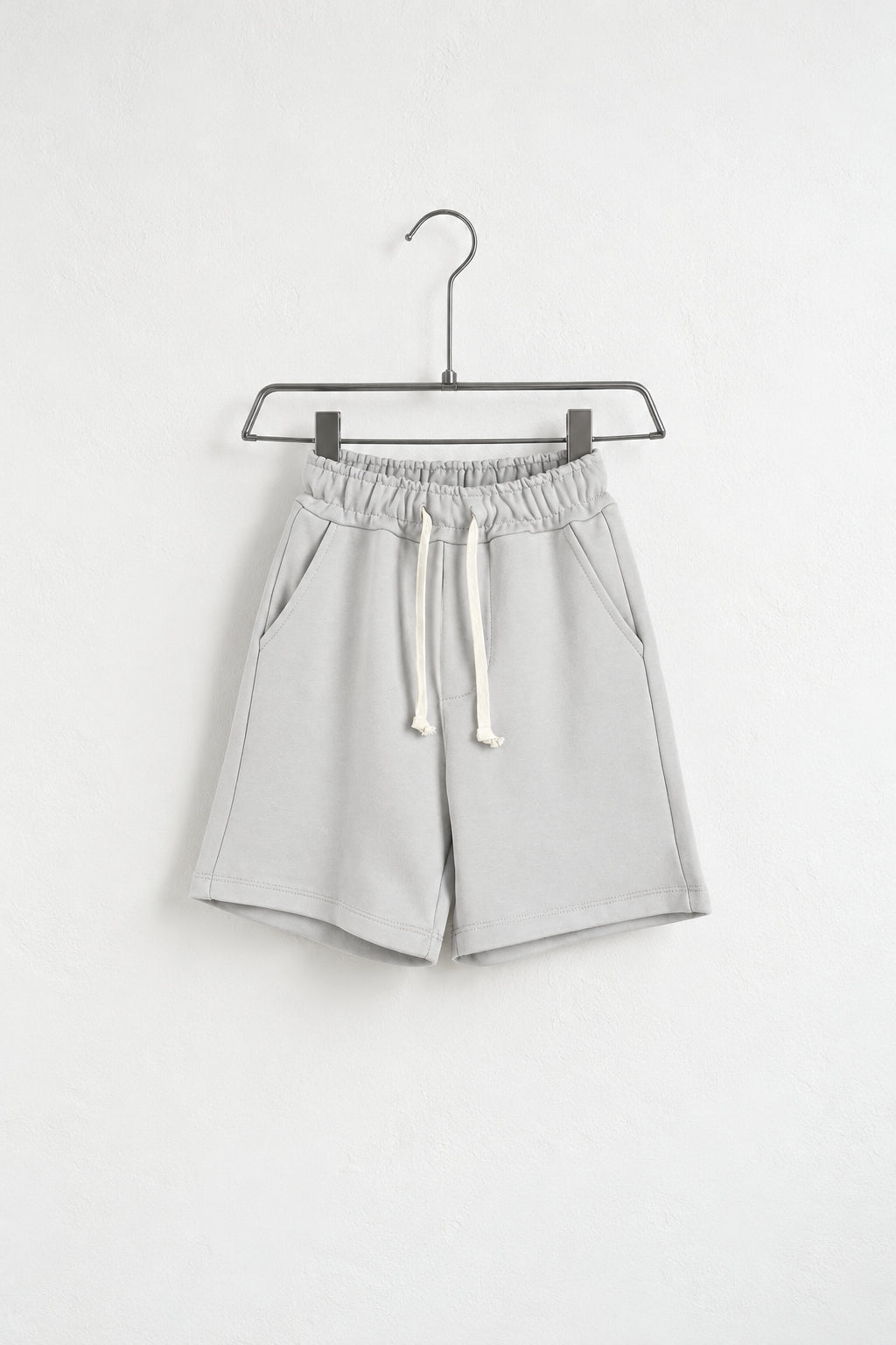 Pantaloni scurți gri deschis pentru copii pe umeraș, vedere oblică
