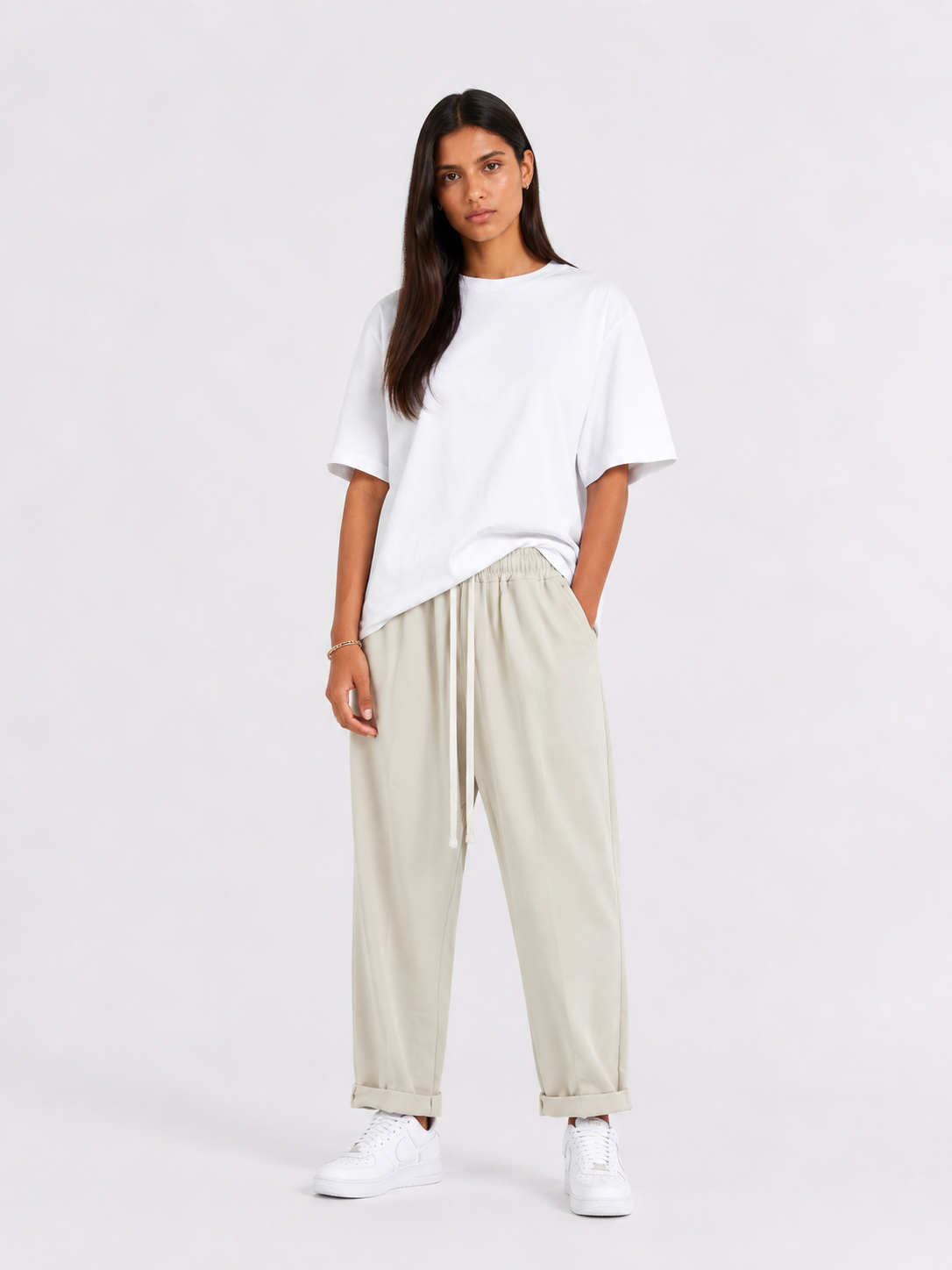 Femeie purtând pantaloni crem cu șiret lung într-un look casual modern și relaxat.