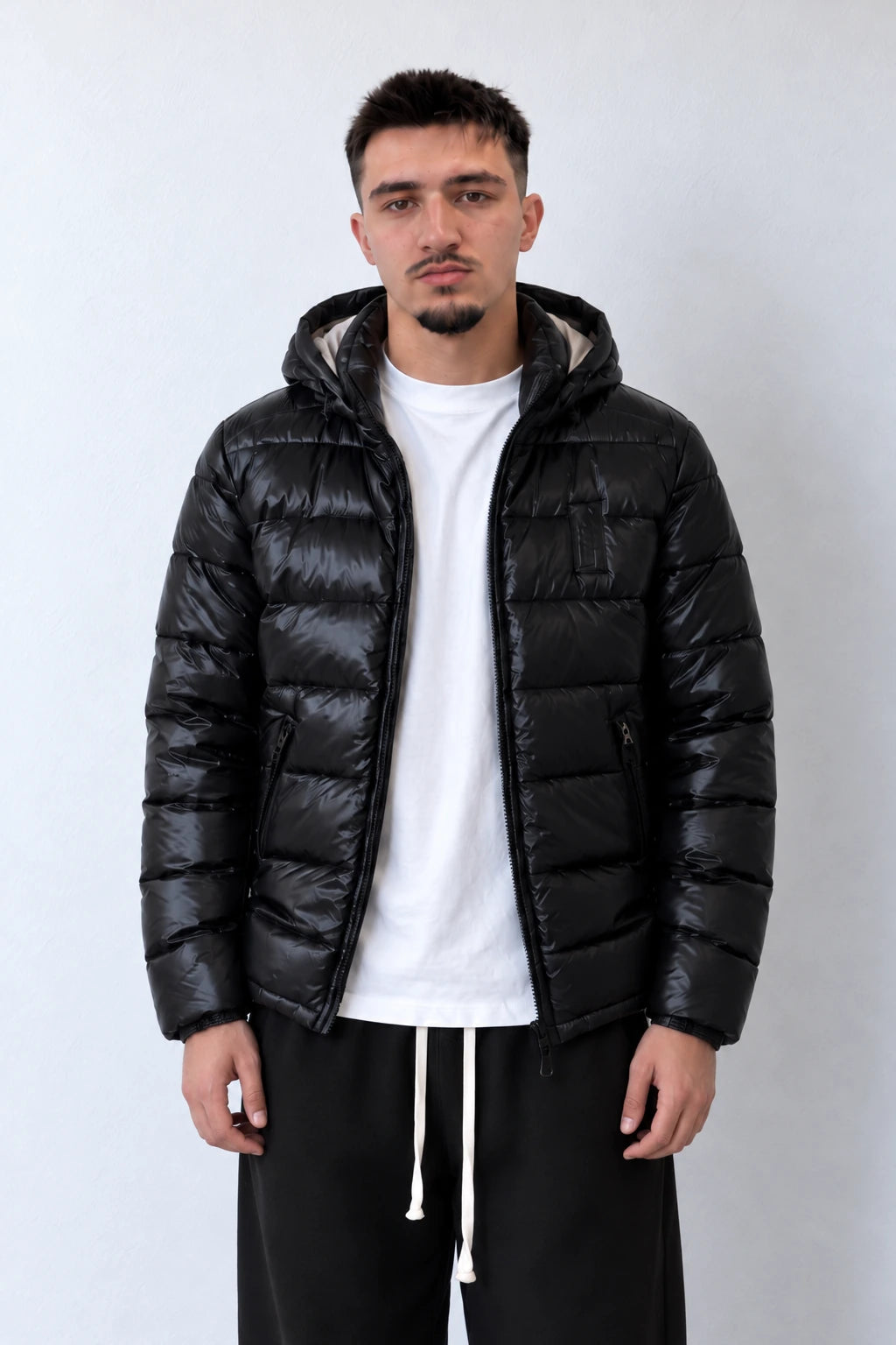 Geacă puffer neagră pentru bărbați, cu glugă și buzunare cu fermoar, vedere frontală apropiată pe model.