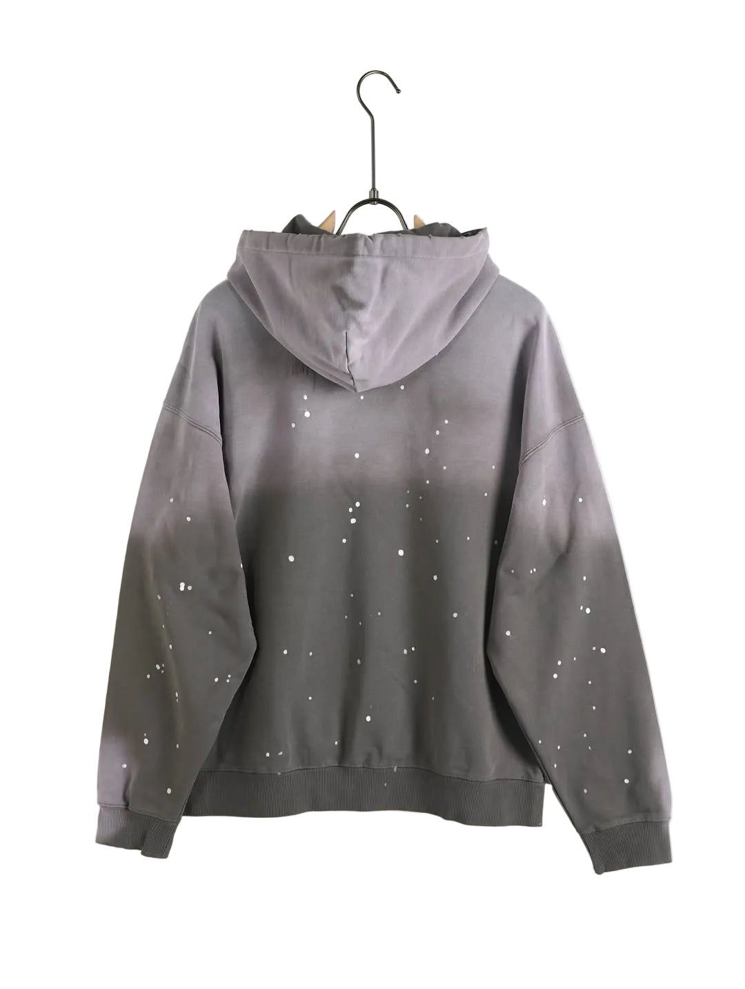 Bărbat într-o ținută lejeră purtând un hanorac cu design din stropi de vopsea gri și mov