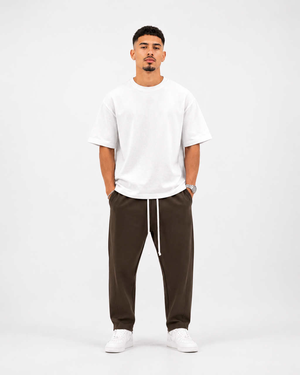 Ședință foto studio pentru pantaloni maro premium streetwear asortați cu tricou alb oversized și pantofi sport albi, stil modern minimalist