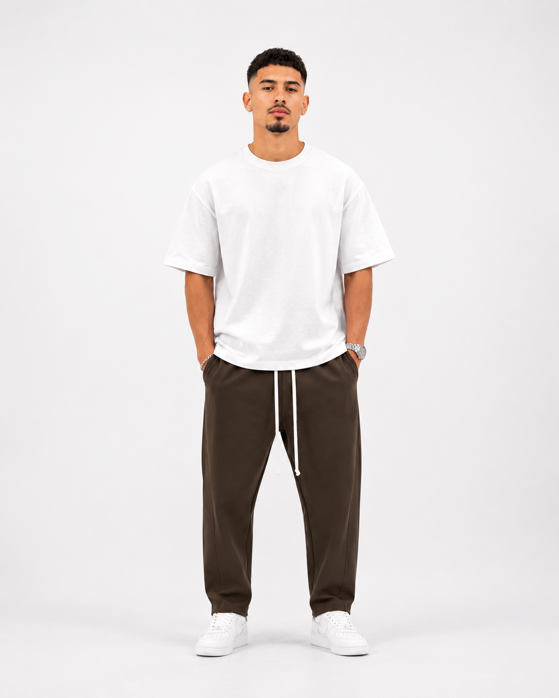Ședință foto studio pentru pantaloni maro premium streetwear asortați cu tricou alb oversized și pantofi sport albi, stil modern minimalist