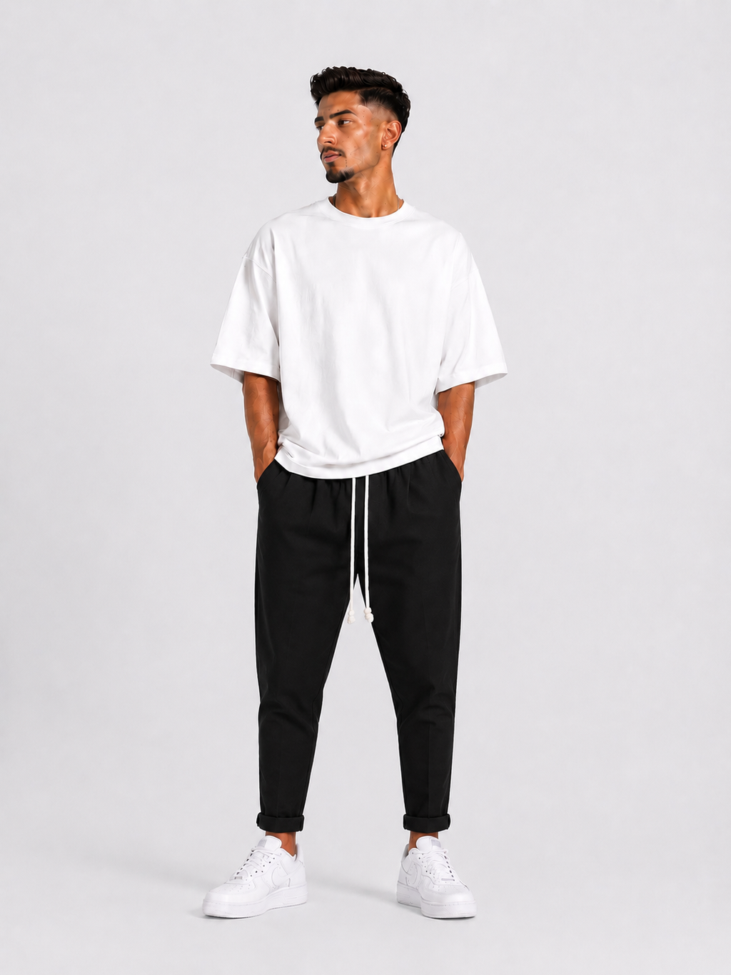 Model masculin cu pantaloni casual negri și șnur lung pentru un look urban minimalist.