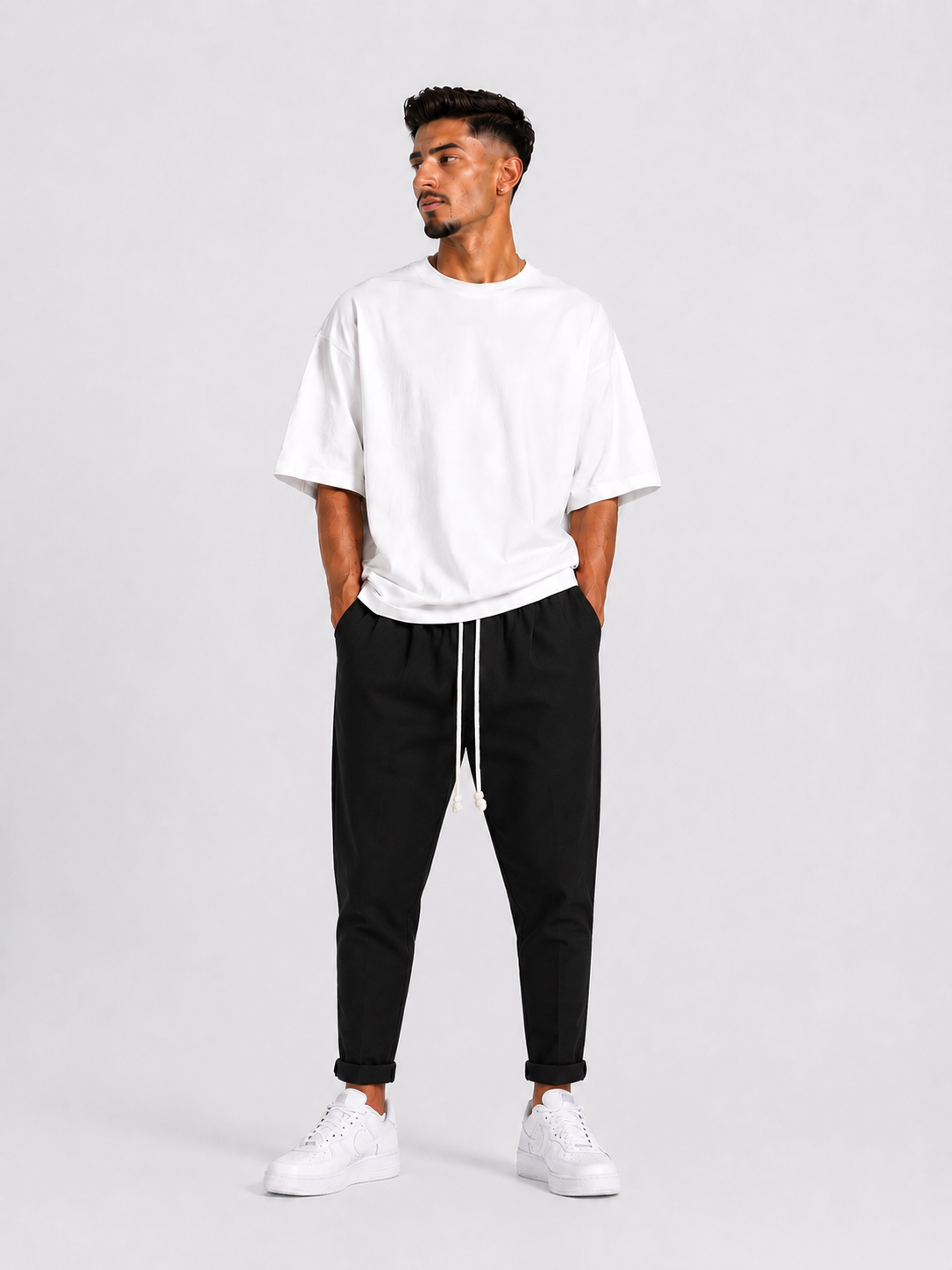 Model masculin cu pantaloni casual negri și șnur lung pentru un look urban minimalist.