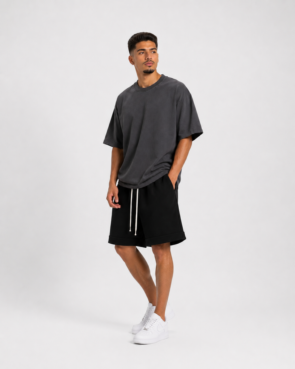 Model masculin purtând tricou gri cu rupturi și outfit minimalist streetwear