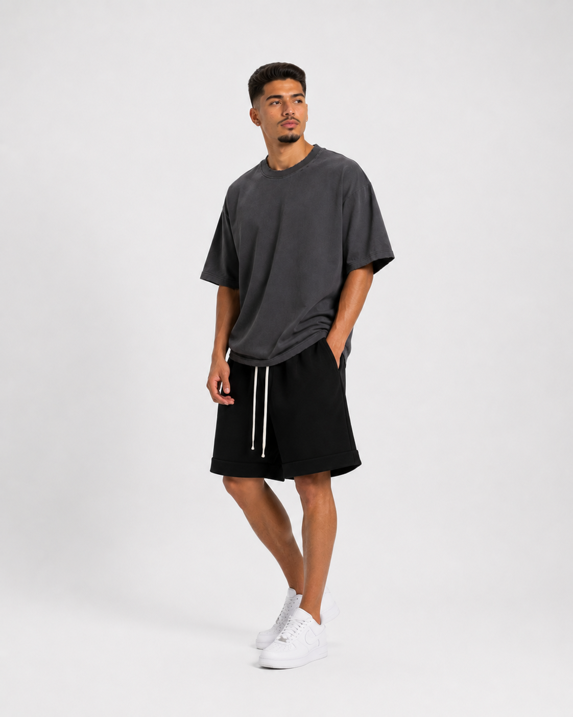 Model masculin purtând tricou gri cu rupturi și outfit minimalist streetwear