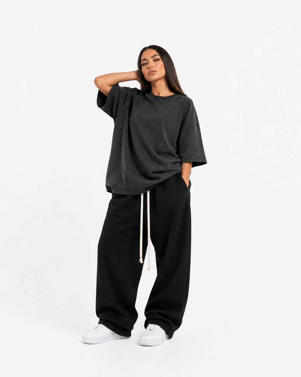 Model feminin purtând haine masculine oversized: pantaloni negri wide leg cu șnur lung și tricou washed charcoal oversized, luxury streetwear aesthetic.