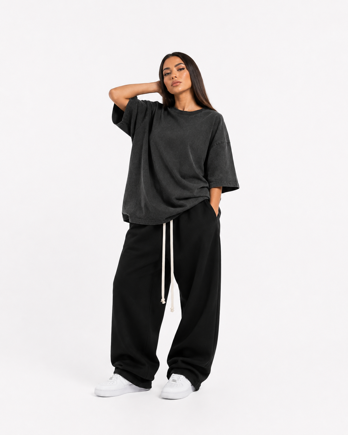 Model feminin purtând haine masculine oversized: pantaloni negri wide leg cu șnur lung și tricou washed charcoal oversized, luxury streetwear aesthetic.