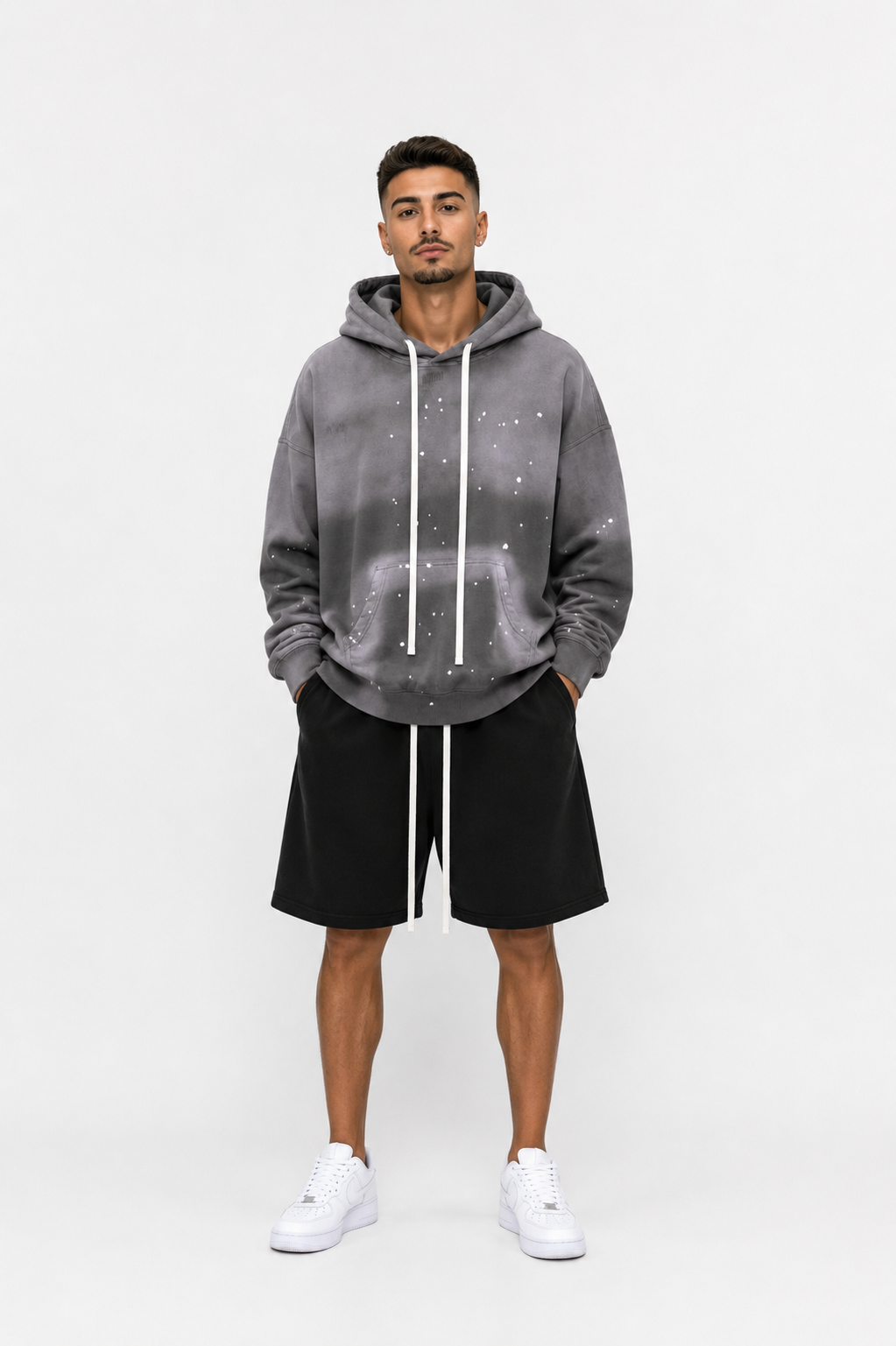 Model masculin purtând hanorac oversized gri cu șnur lung și pantaloni scurți streetwear premium