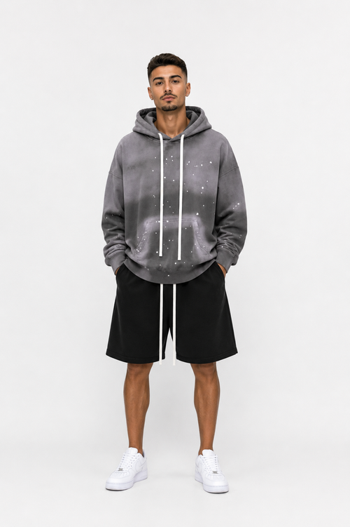 Model masculin purtând hanorac oversized gri cu șnur lung și pantaloni scurți streetwear premium
