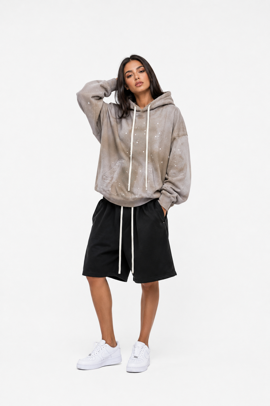 Femeie cu hoodie bej oversized și șnururi lungi albe într-o ținută urban premium