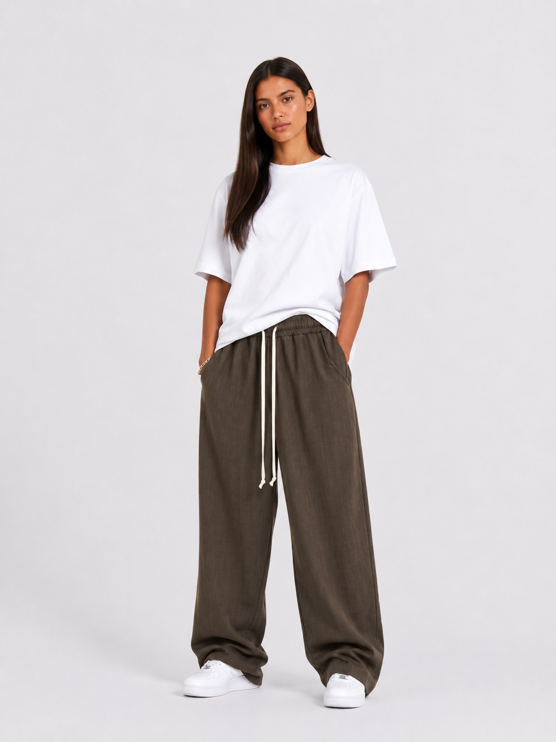 Outfit feminin modern cu pantaloni maro wide leg și siret lung pentru stil relaxat și urban.