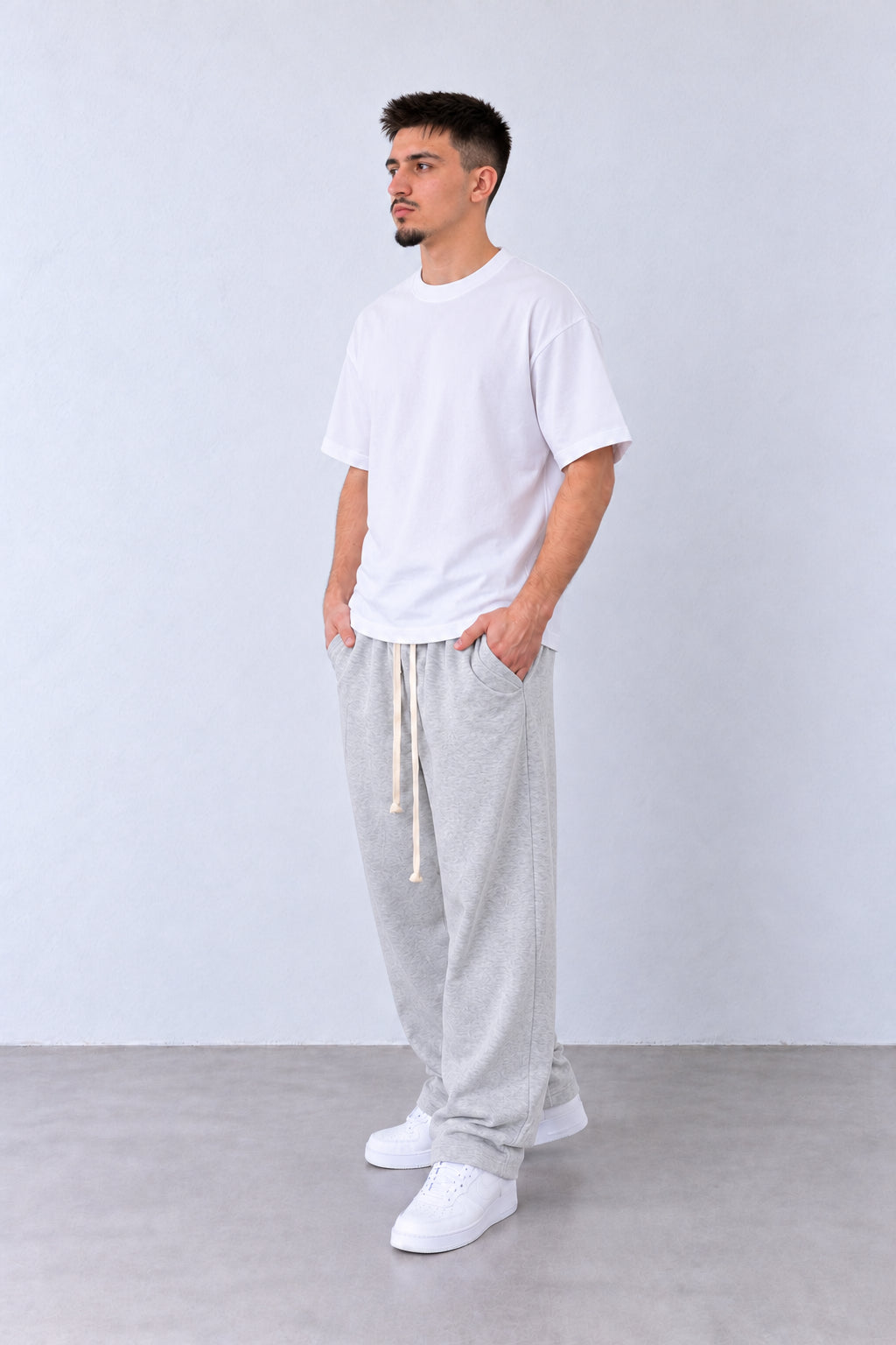 Pantaloni Baggy Felpați Bărbați Gri Melanj, vedere integrală pe model cu capul ușor întors sau înclinat.