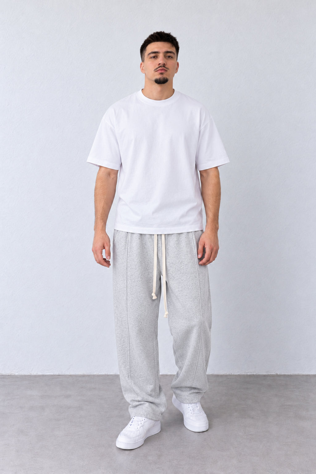 Pantaloni Baggy Felpați Bărbați Gri Melanj, vedere pe model cu poziție alternativă a brațelor și picioarelor.