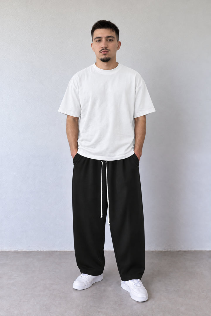 Pantaloni baggy negri 202501-INV pentru bărbați, vedere frontală pe model cu tricou alb și șnur lung