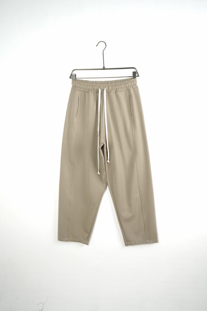 Pantaloni bej baggy pentru bărbați, cu șnururi albe și cusături laterale, vedere frontală integrală pe umeraș