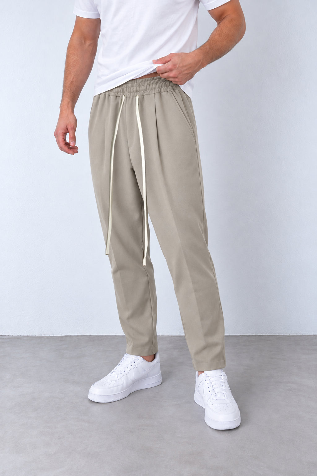 Pantaloni bej pe model, vedere din trei sferturi cu talie elastică și șnur lung.