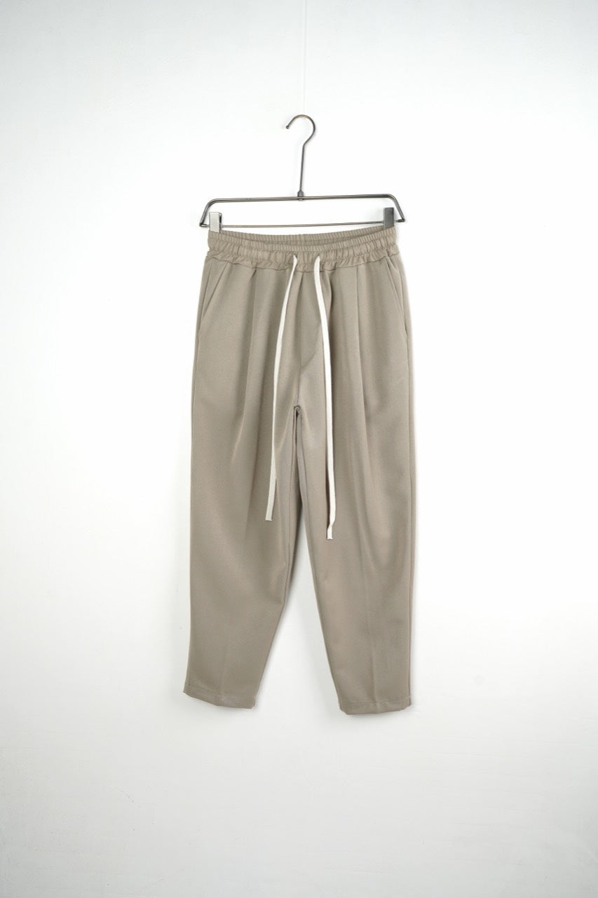 Pantaloni bej carrot fit pentru bărbați, cu talie elastică și șnururi albe, vedere frontală integrală pe umeraș