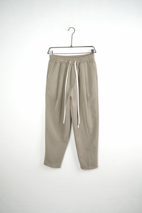 Pantaloni bej carrot fit pentru bărbați, cu talie elastică și șnururi albe, vedere frontală integrală pe umeraș