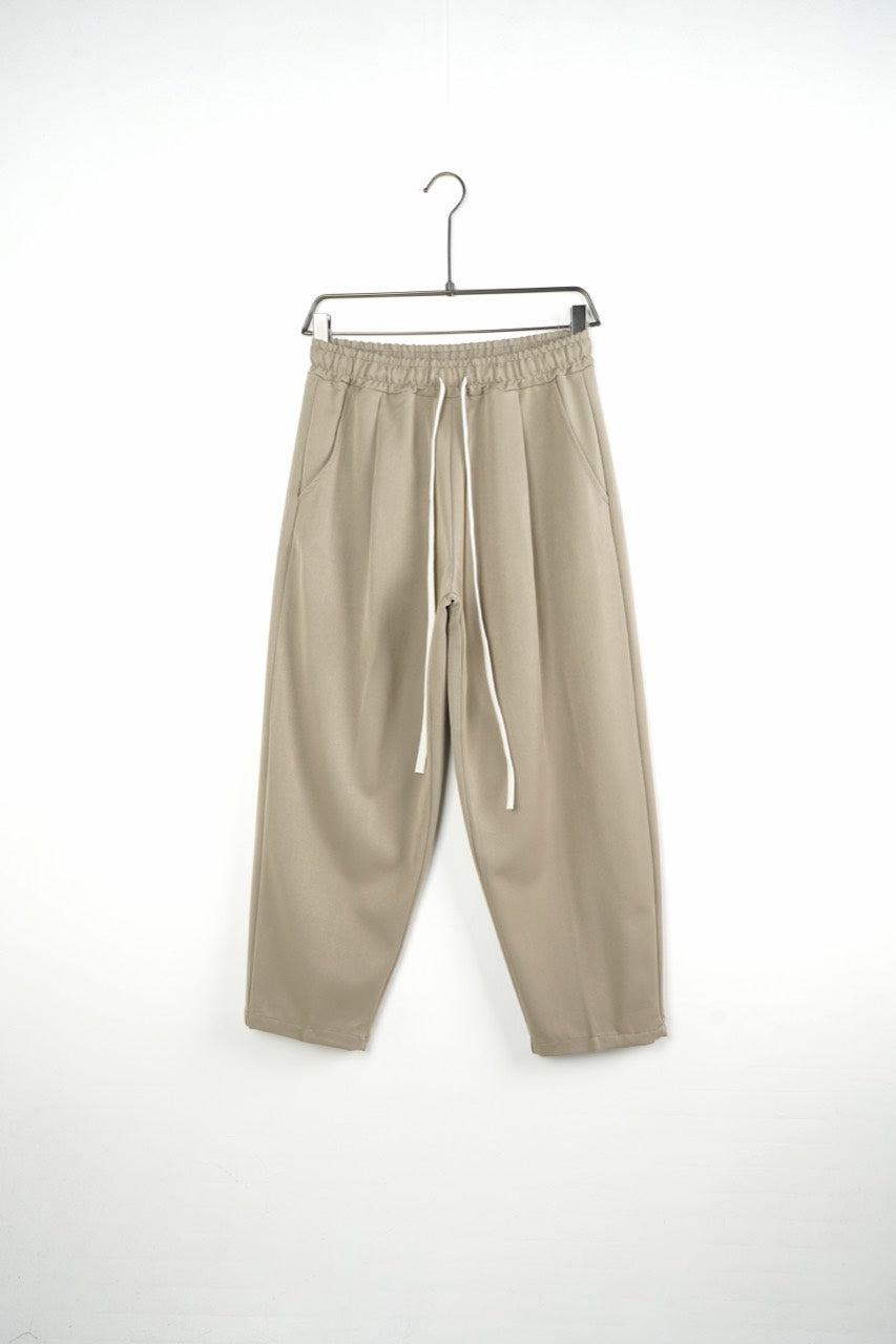 Pantaloni bej baggy pentru bărbați, cu talie elastică și șnururi albe, vedere frontală integrală pe umeraș