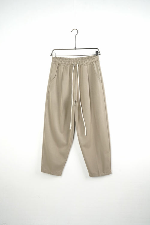 Pantaloni bej baggy pentru bărbați, cu talie elastică și șnururi albe, vedere frontală integrală pe umeraș