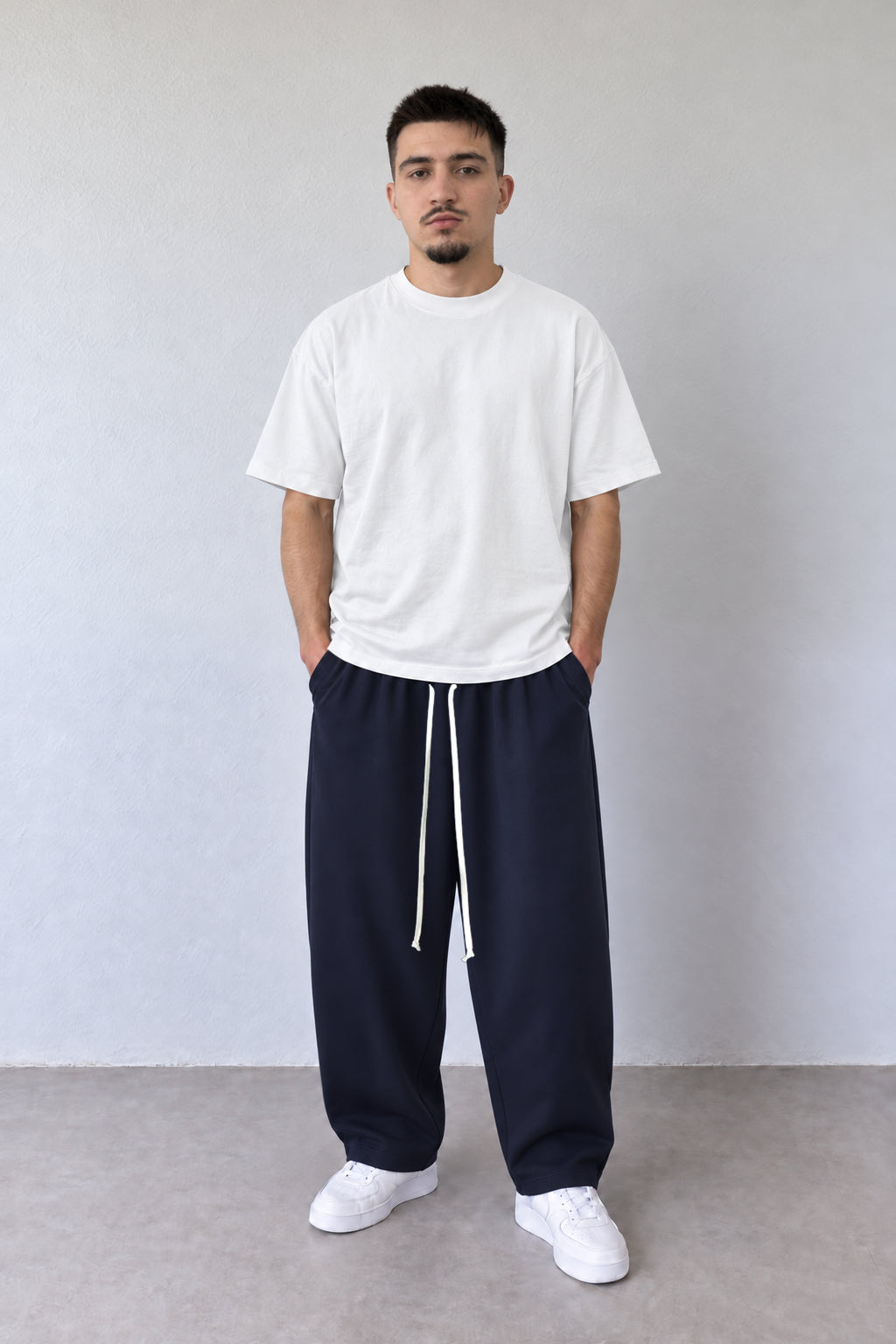 Pantaloni baggy bleumarin pentru bărbați, vedere frontală pe model cu tricou alb și șnur lung