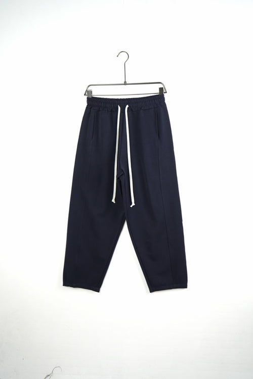 Pantaloni bleumarin baggy pentru bărbați, cu șnururi albe și cusături laterale, vedere frontală integrală pe umeraș