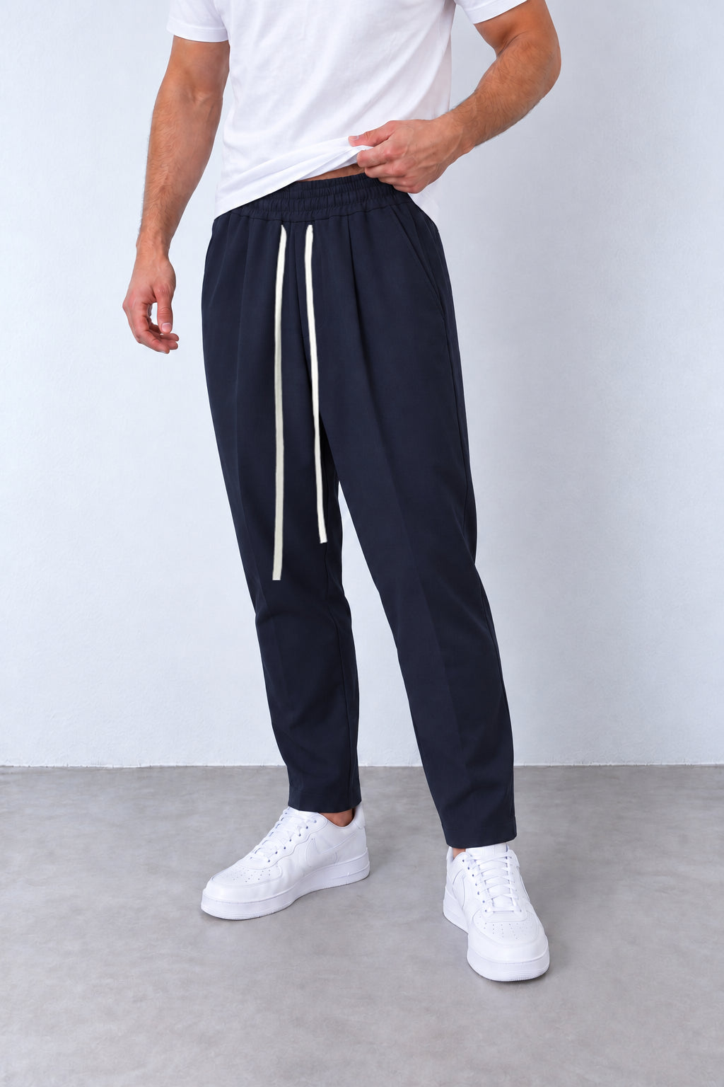 Pantaloni bleumarin pe model, vedere din trei sferturi cu talie elastică și șnur lung.