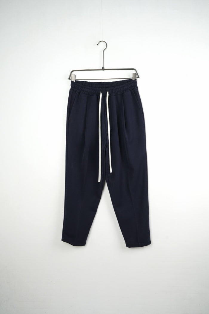 Pantaloni bleumarin carrot fit pentru bărbați, cu talie elastică și șnururi albe, vedere frontală integrală pe umeraș