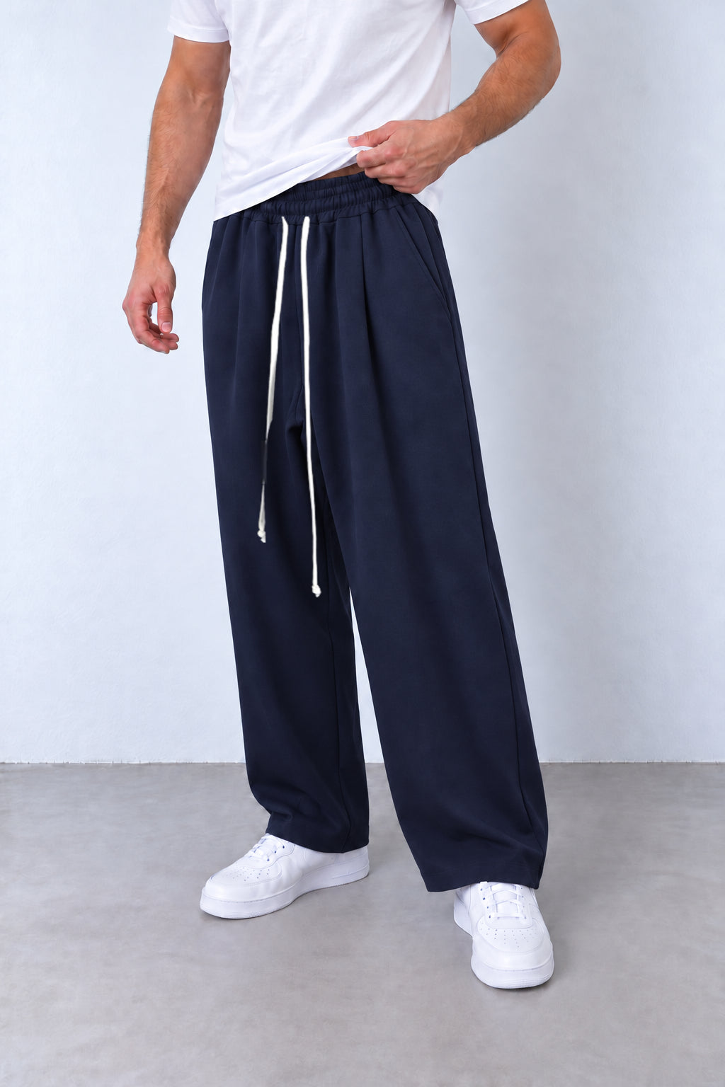 Pantaloni baggy bleumarin pe model, cadru din trei sferturi cu talie elastică și șnur lung.