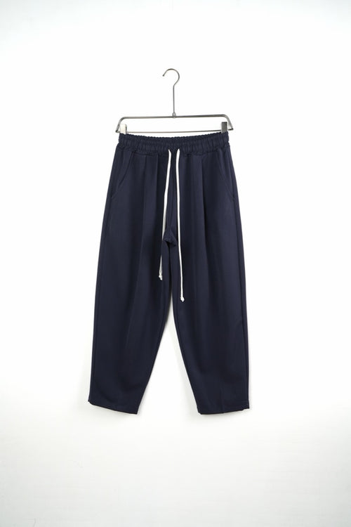 Pantaloni bleumarin baggy pentru bărbați, cu talie elastică și șnururi albe, vedere frontală integrală pe umeraș