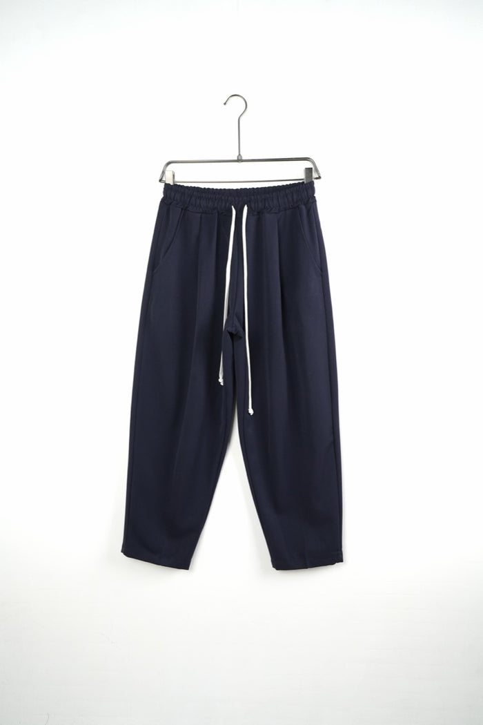 Pantaloni bleumarin baggy pentru bărbați, cu talie elastică și șnururi albe, vedere frontală integrală pe umeraș