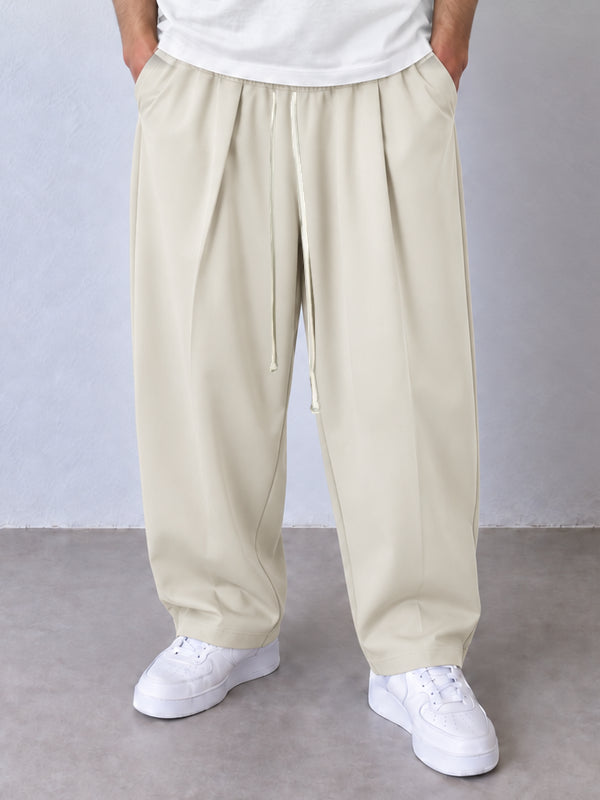 Pantaloni crem, cadru frontal apropiat cu pense, șnur lung și tivuri simple.
