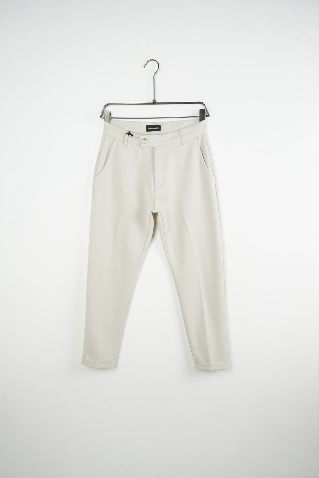 Pantaloni crem slim fit pentru bărbați, cu nasture, găici pentru curea și tiv cu rever, vedere frontală pe umeraș