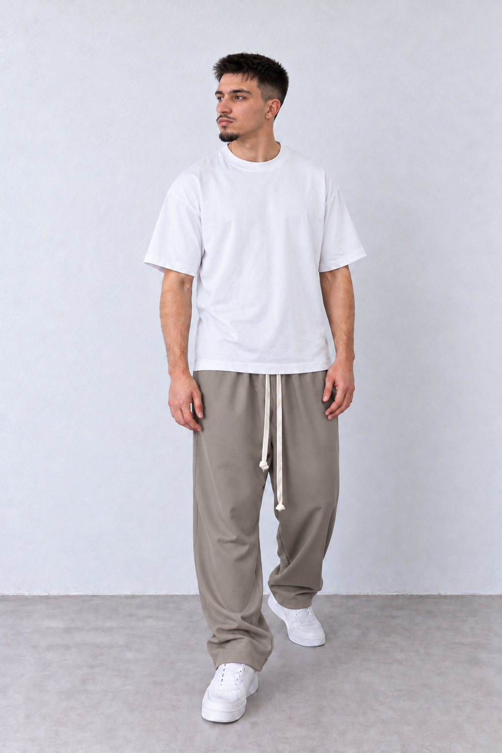 Pantaloni Bărbați Grej Largi cu Șnur Lung, vedere pe model cu poziție alternativă a brațelor și picioarelor.