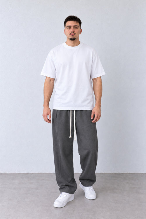Pantaloni baggy gri pentru bărbați, cu șnur lung și cusătură laterală lângă buzunar, ținută integrală pe model.