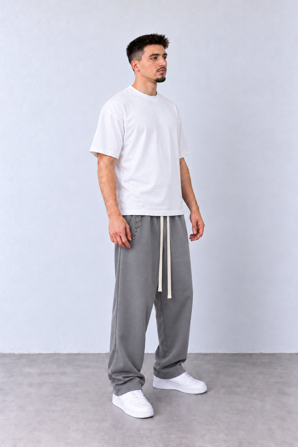 Pantaloni Bărbați Gri Largi cu Inele Decorative, vedere integrală pe model cu capul ușor întors sau înclinat.