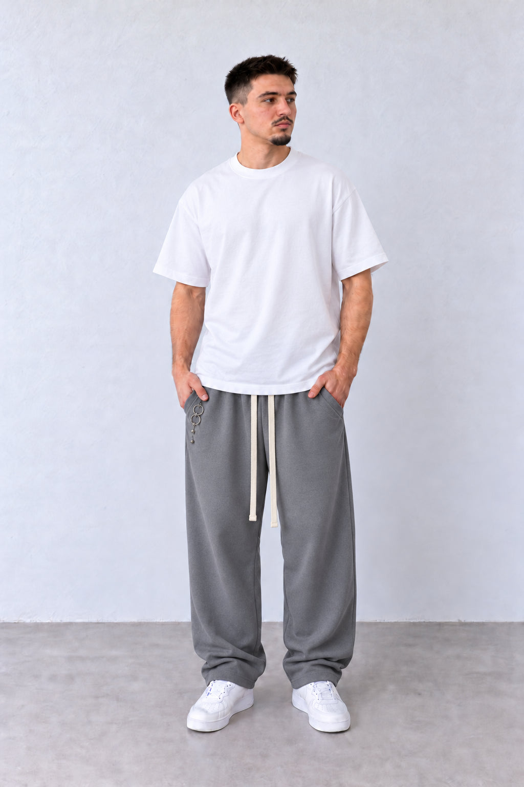 Pantaloni Bărbați Gri Largi cu Inele Decorative, vedere pe model cu poziție alternativă a brațelor și picioarelor.